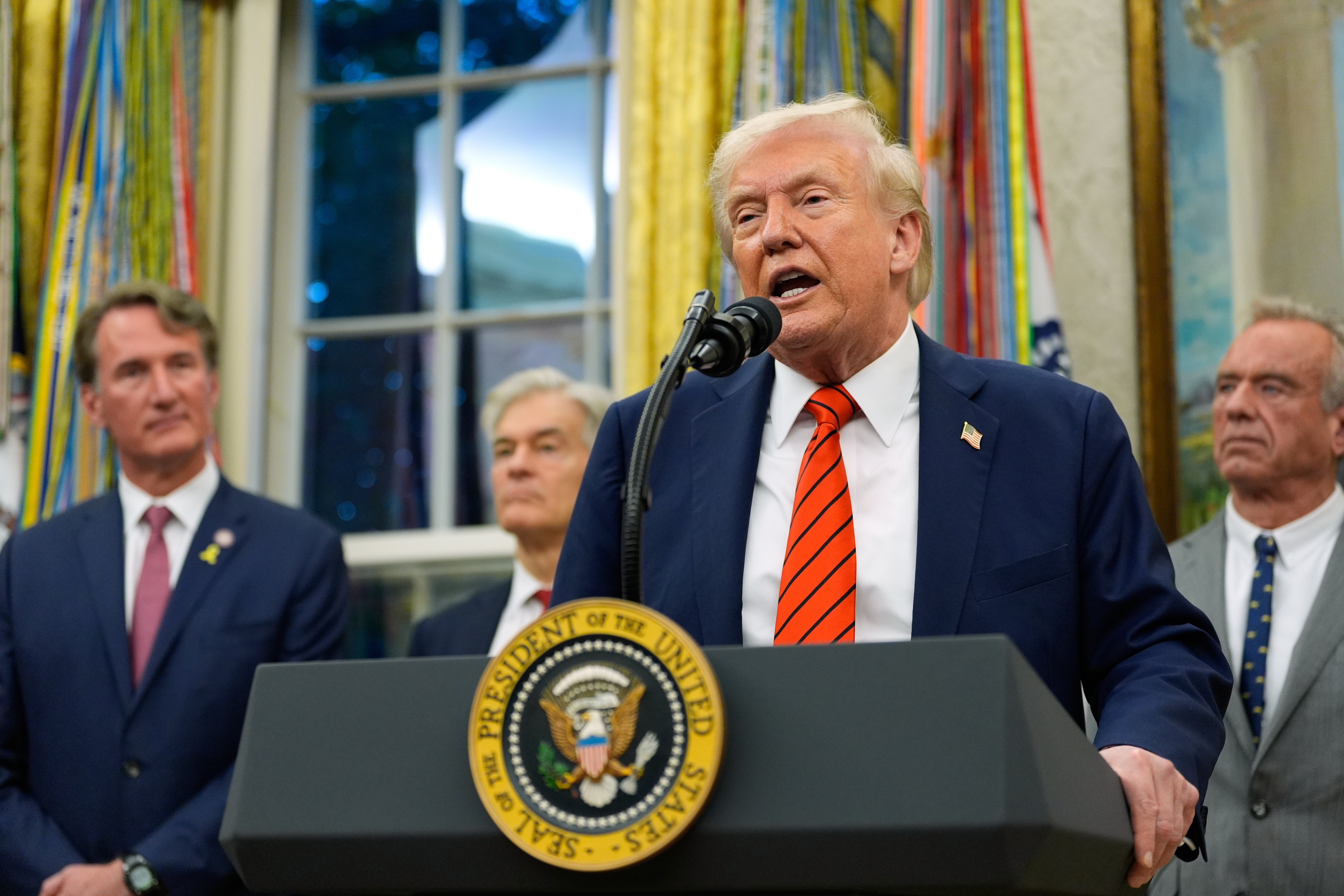 President Donald Trump speaks in the Oval Office of the White House, Friday, Oct. 10, 2025, in Washington, as Virginia Gov. Glenn Youngkin, Centers for Medicare & Medicaid Services administrator Dr. Mehmet Oz and Health and Human Services Secretary Robert F. Kennedy Jr., listen.